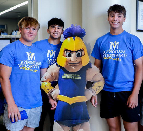 three students st和 smiling with a cutout of Cruzer